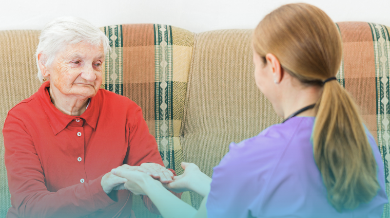Why Our Carers Stay: What Makes Working In Domiciliary Care So Rewarding - Universal Care Services Domiciliary Care, Client And Carer, Client Is An Older Lady Wearing A Red Jumper And Grey Hair. Care Worker Is Wearing A Lilac Tunic